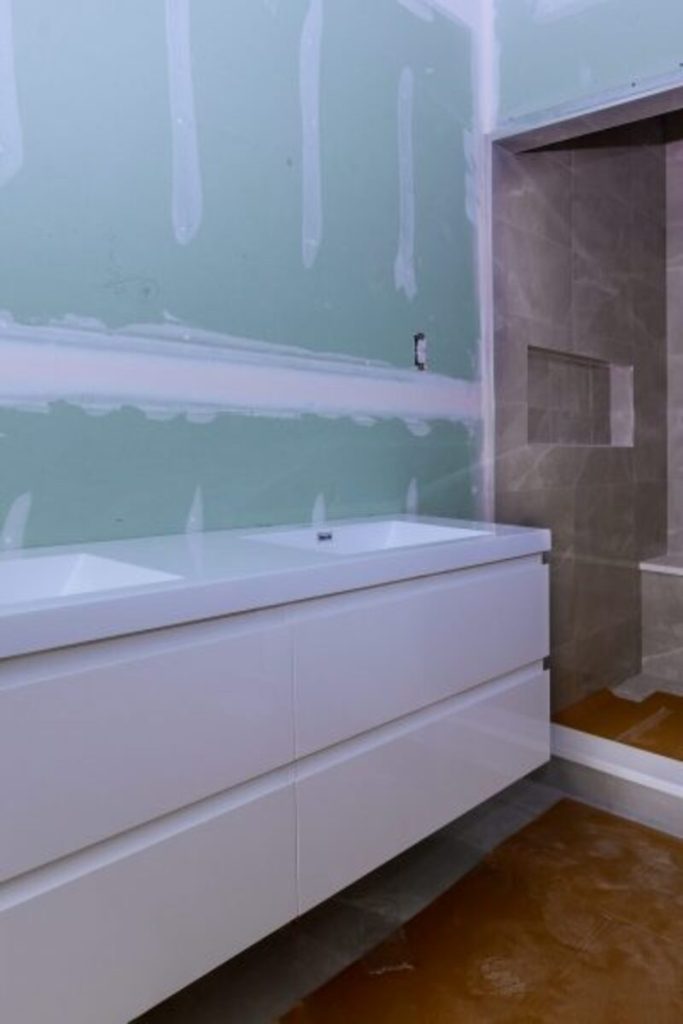 Moisture-resistant green drywall panels installed in bathroom wall before tile finishing